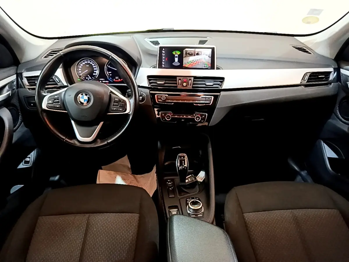 Intérieur BMW X1 2020 vu de face, tableau de bord noir avec écran tactile et volant cuir multifonctions.