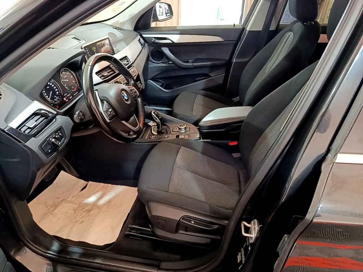 Intérieur avant droit d'une BMW X1 noir 2020, volant cuir multifonctions et écran tactile 8,8 pouces visible.