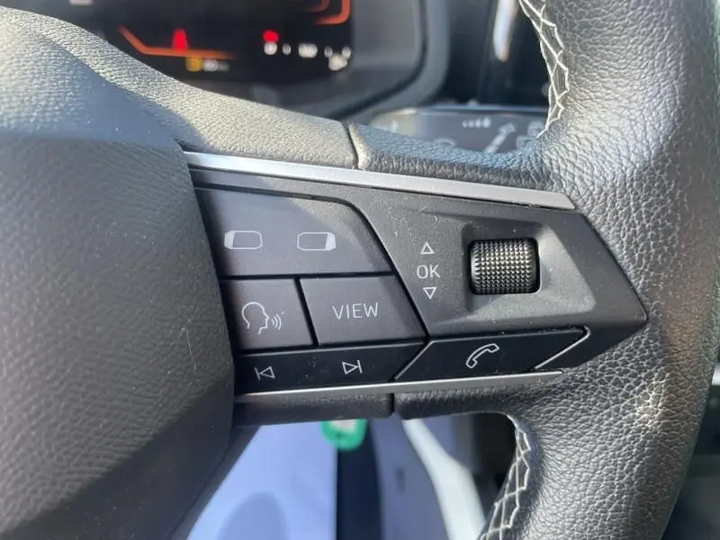 Gros plan sur les commandes au volant côté gauche du SEAT Arona noir 2023, mettant en valeur les boutons multifonctions.
