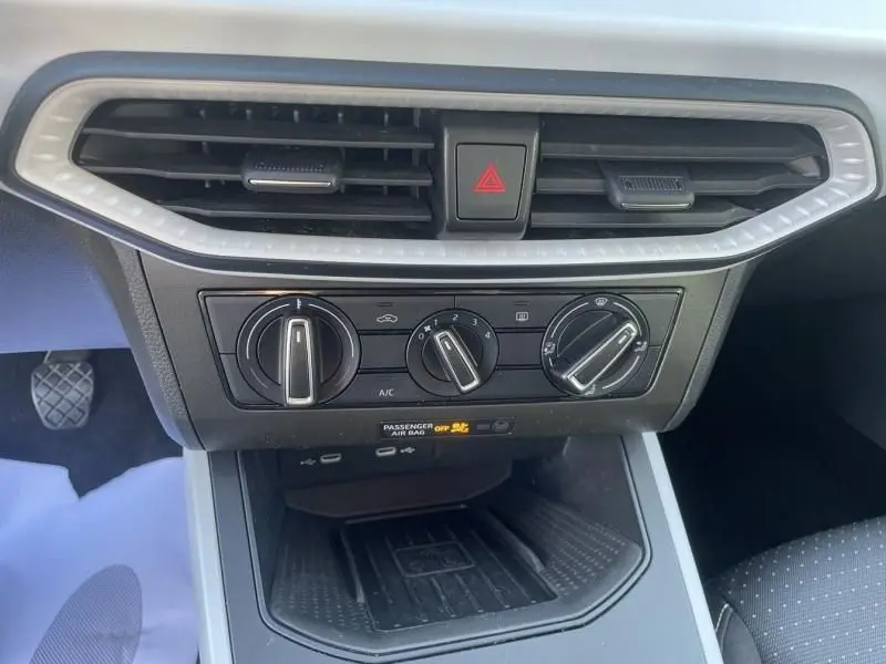 Vue rapprochée de la console centrale du SEAT Arona noir 2023, avec commandes manuelles de climatisation et aérateurs.