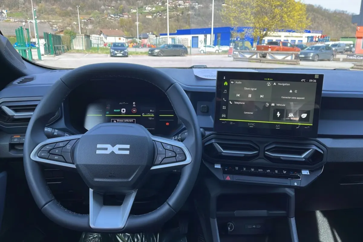 Vue intérieure du tableau de bord du Dacia Bigster Hybrid 155 Expression Plus, avec volant cuir et écran tactile central 10,1 pouces.