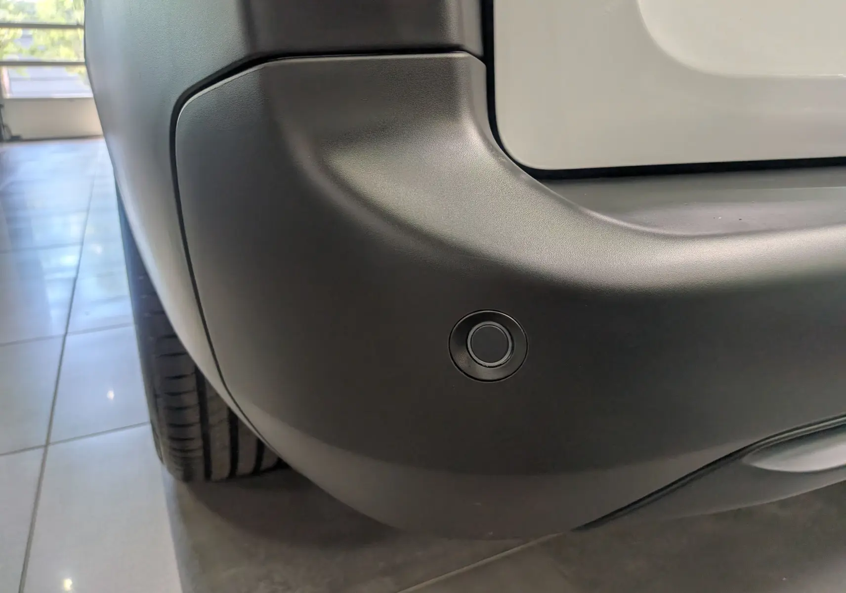Gros plan sur le pare-chocs arrière droit blanc glacier du Toyota Proace City avec capteur de recul intégré.