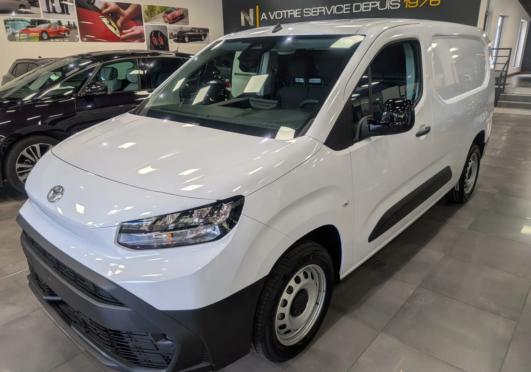 Toyota Proace City Long blanc glacier vue 3/4 avant droit en showroom avec détails noirs sur pare-chocs et rétroviseurs.