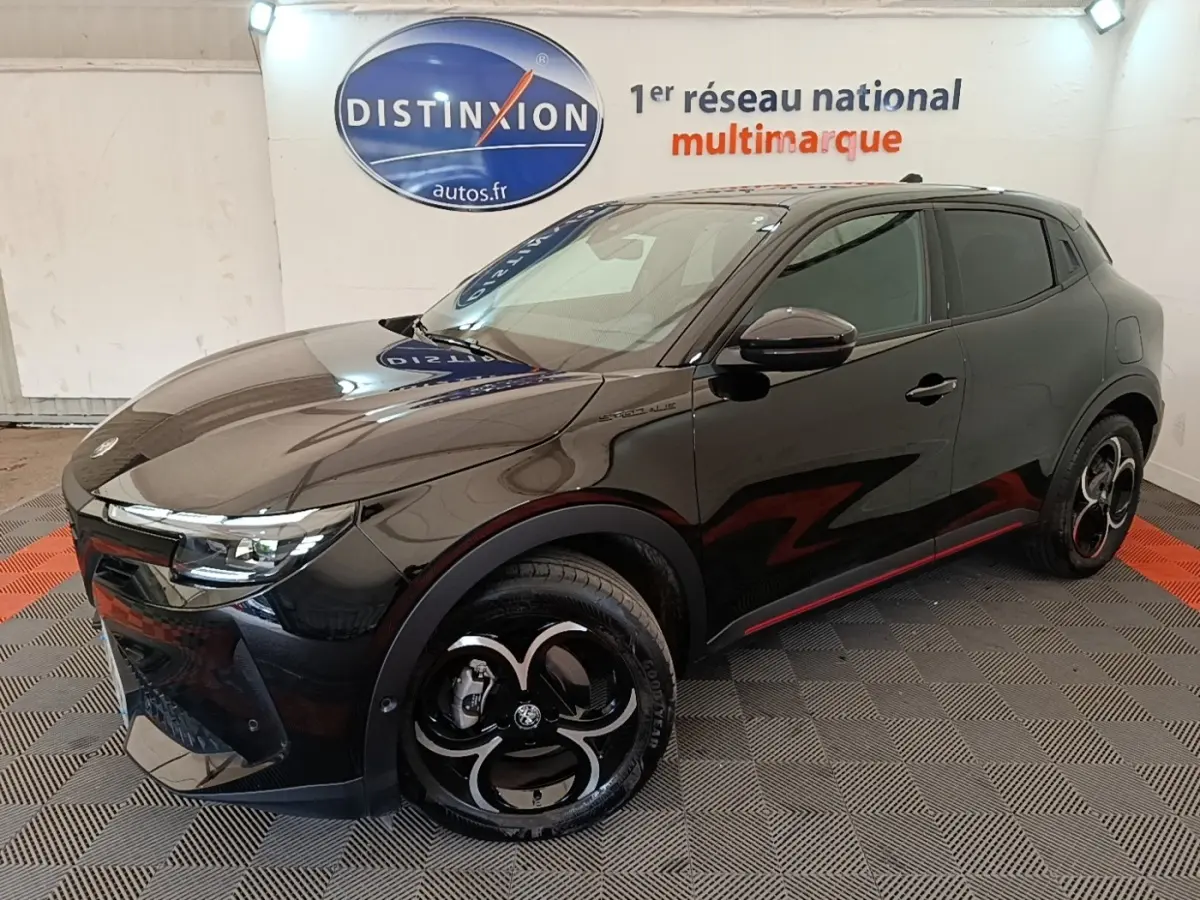 Vue 3/4 avant droit d'une Alfa Romeo Junior 1.2 hybride noire avec jantes noires et détails rouges sur le bas de caisse.