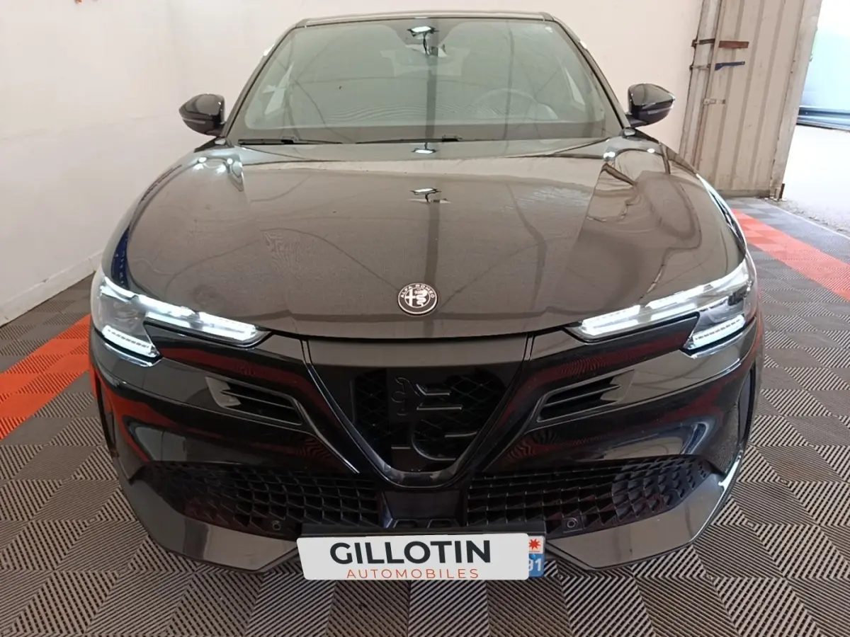 Vue avant d'une Alfa Romeo Junior 1.2 Ibrida noire avec phares LED et calandre distinctive en V.
