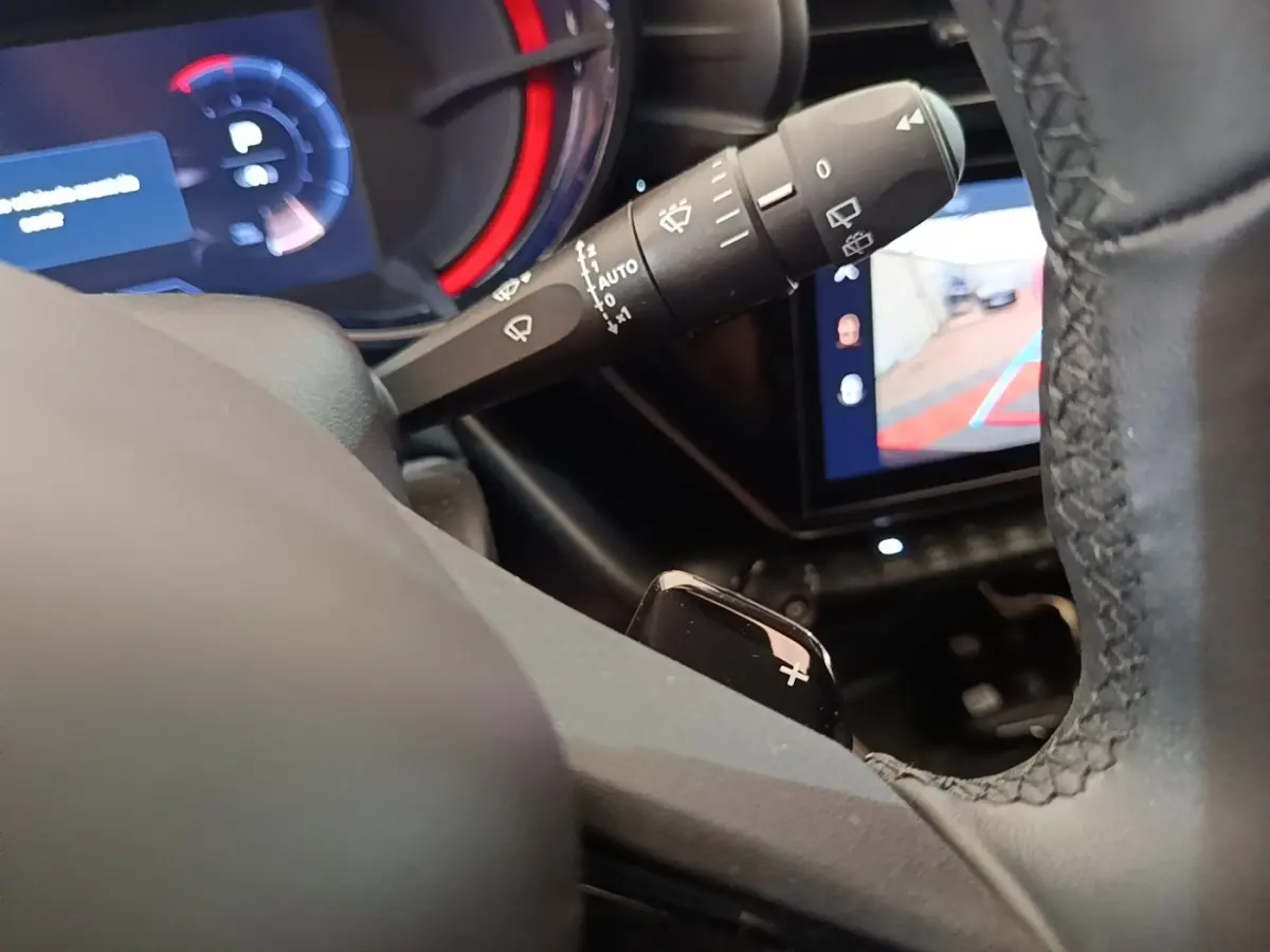 Gros plan intérieur sur le levier de commande des essuie-glaces et le volant noir de l'Alfa Romeo Junior 2024.