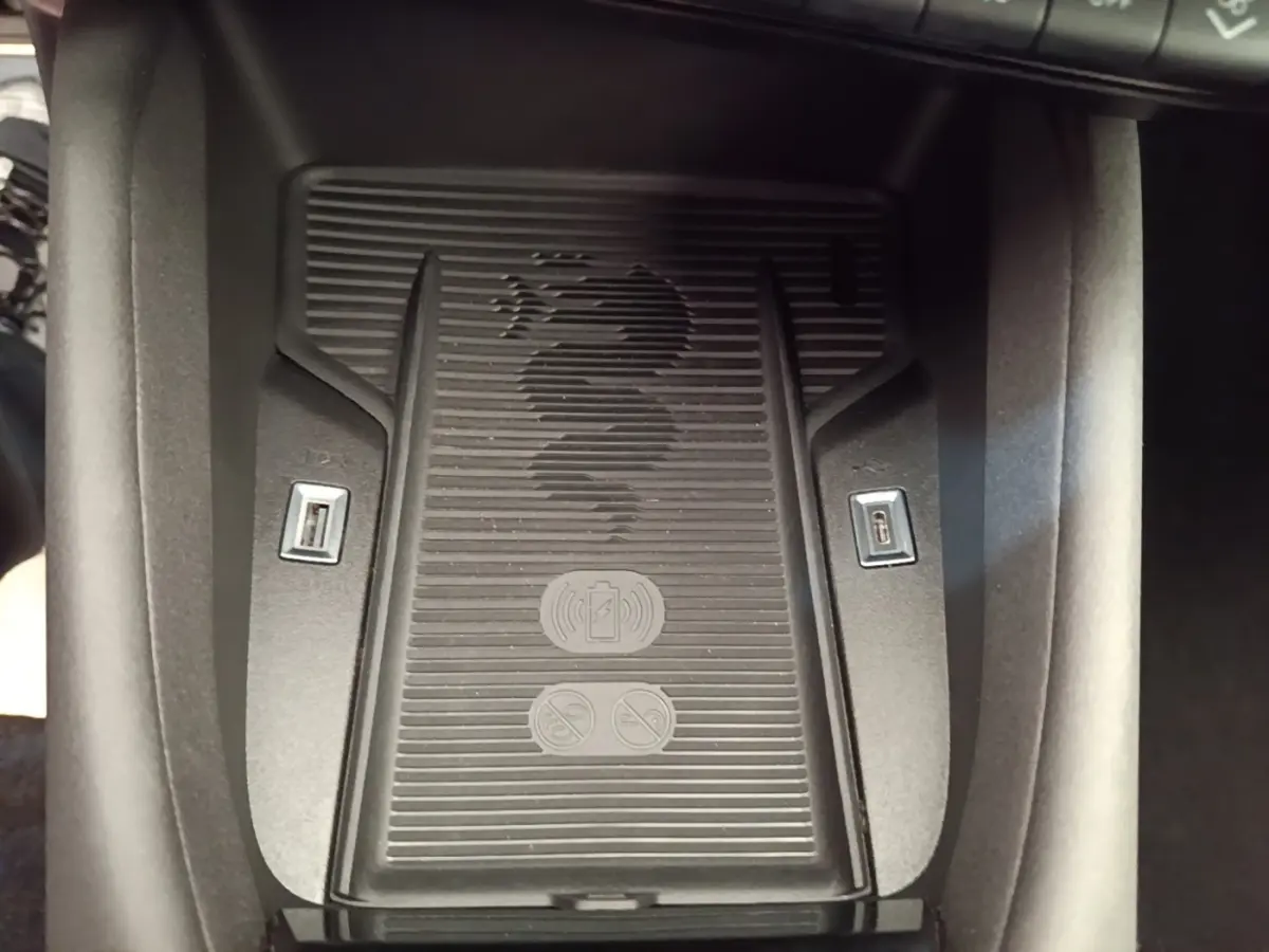 Vue rapprochée du chargeur sans fil noir avec logo Alfa Romeo et ports USB intégrés dans la console centrale.