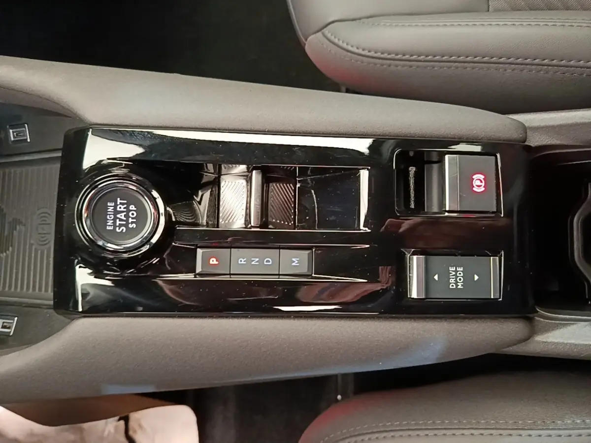 Vue plongeante sur la console centrale noire de l'Alfa Romeo Junior 2024, avec bouton start/stop et commandes boîte auto.