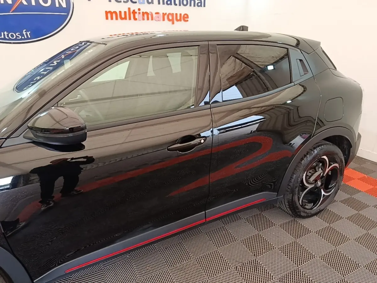 Vue de profil côté gauche de l'Alfa Romeo Junior noire avec jantes noires et détails rouges sur bas de caisse.