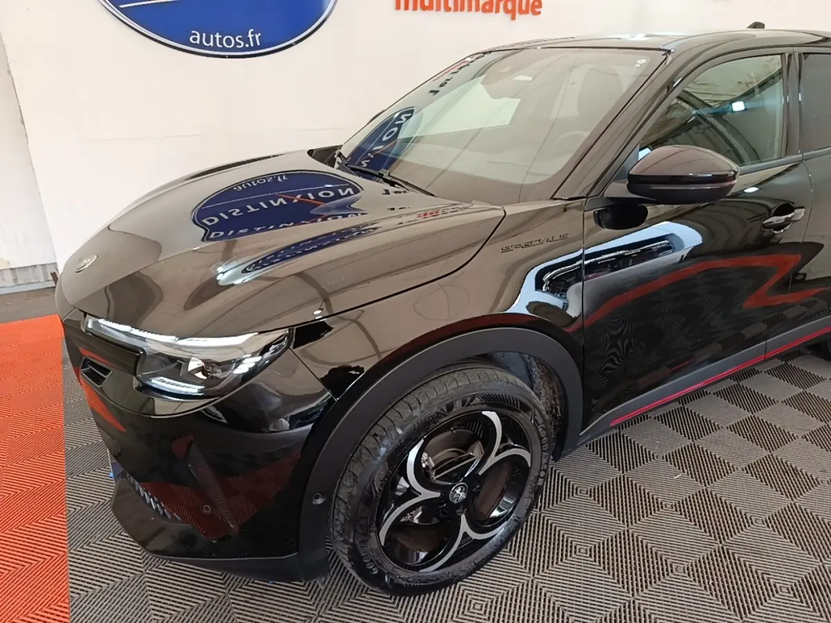 Vue 3/4 avant droit d'une Alfa Romeo Junior noire avec jantes noires et détails rouges sur les bas de caisse.