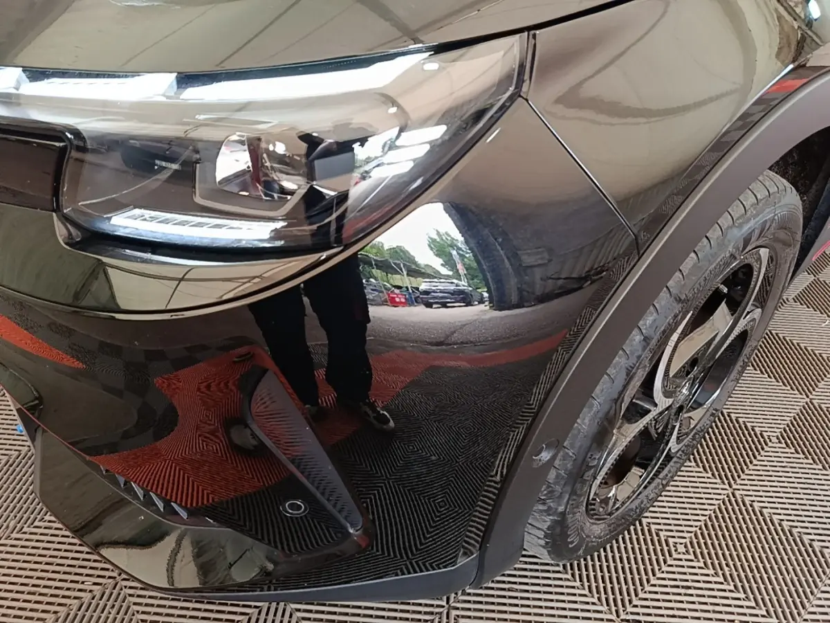 Gros plan sur l'aile avant droite noire d'une Alfa Romeo Junior 2024, mettant en valeur le phare LED et la jante noire.