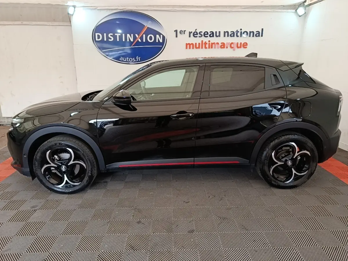 Vue de profil côté gauche d'une Alfa Romeo Junior 1.2 Ibrida noire avec jantes noires et détails rouges sur les bas de caisse.