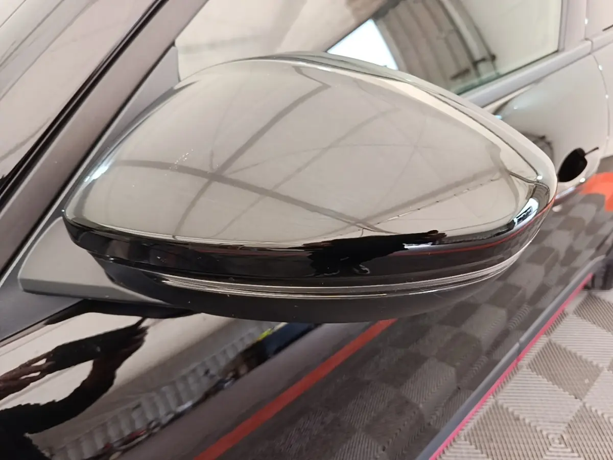 Rétroviseur côté gauche noir brillant de l'Alfa Romeo Junior 1.2 Ibrida 136ch Speciale DCT6 2024, reflet de l'environnement intérieur.