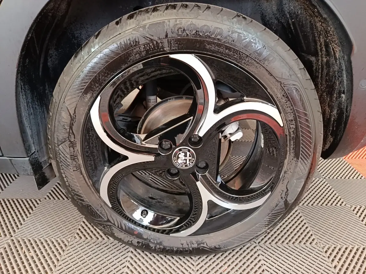 Gros plan sur la roue avant droite noire avec jante en alliage bicolore au design en trois branches d'Alfa Romeo Junior.