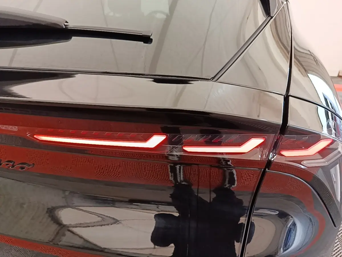 Gros plan sur le feu arrière droit allumé d'une Alfa Romeo Junior noire, avec reflet brillant sur la carrosserie.