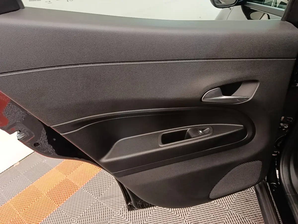 Vue intérieure de la porte arrière droite noire de l'Alfa Romeo Junior 1.2 Ibrida 2024 avec poignée et commande de fenêtre.