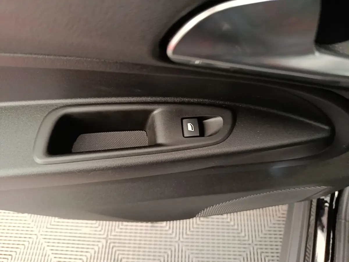 Gros plan sur la commande de lève-vitre côté gauche de la porte intérieure noire d’une Alfa Romeo Junior 2024.