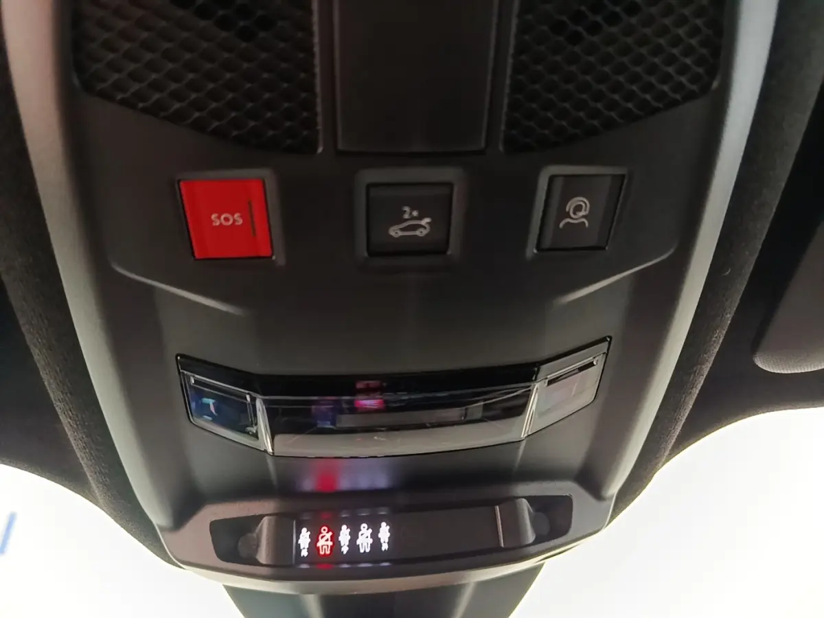 Vue en gros plan du panneau de commandes au plafond de l'Alfa Romeo Junior 1.2 Ibrida, avec bouton SOS rouge et éclairage des ceintures.