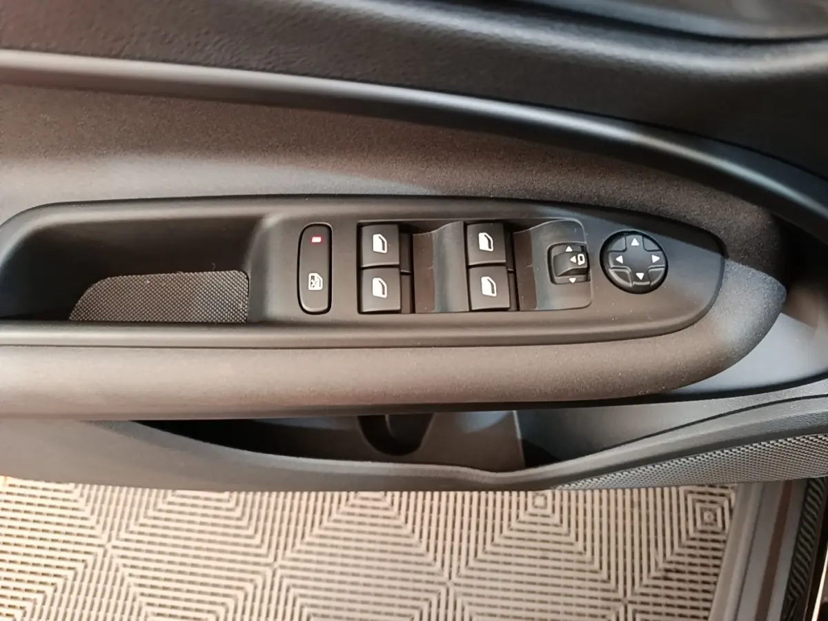Gros plan sur la commande des vitres et rétroviseurs côté gauche de la porte d'une Alfa Romeo Junior noire.