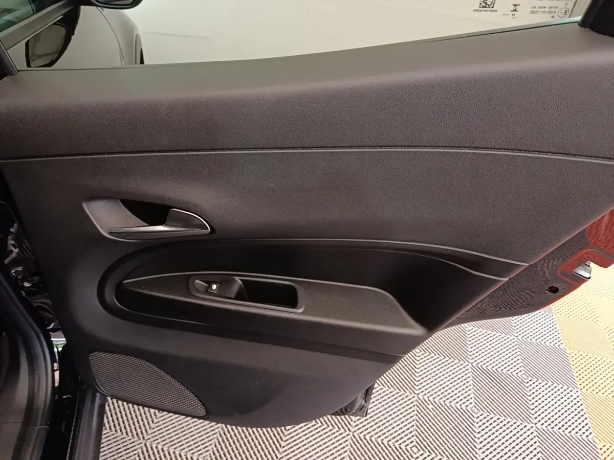 Vue intérieure sur la porte côté gauche noire de l'Alfa Romeo Junior 2024 avec poignée et commande de vitre électrique.