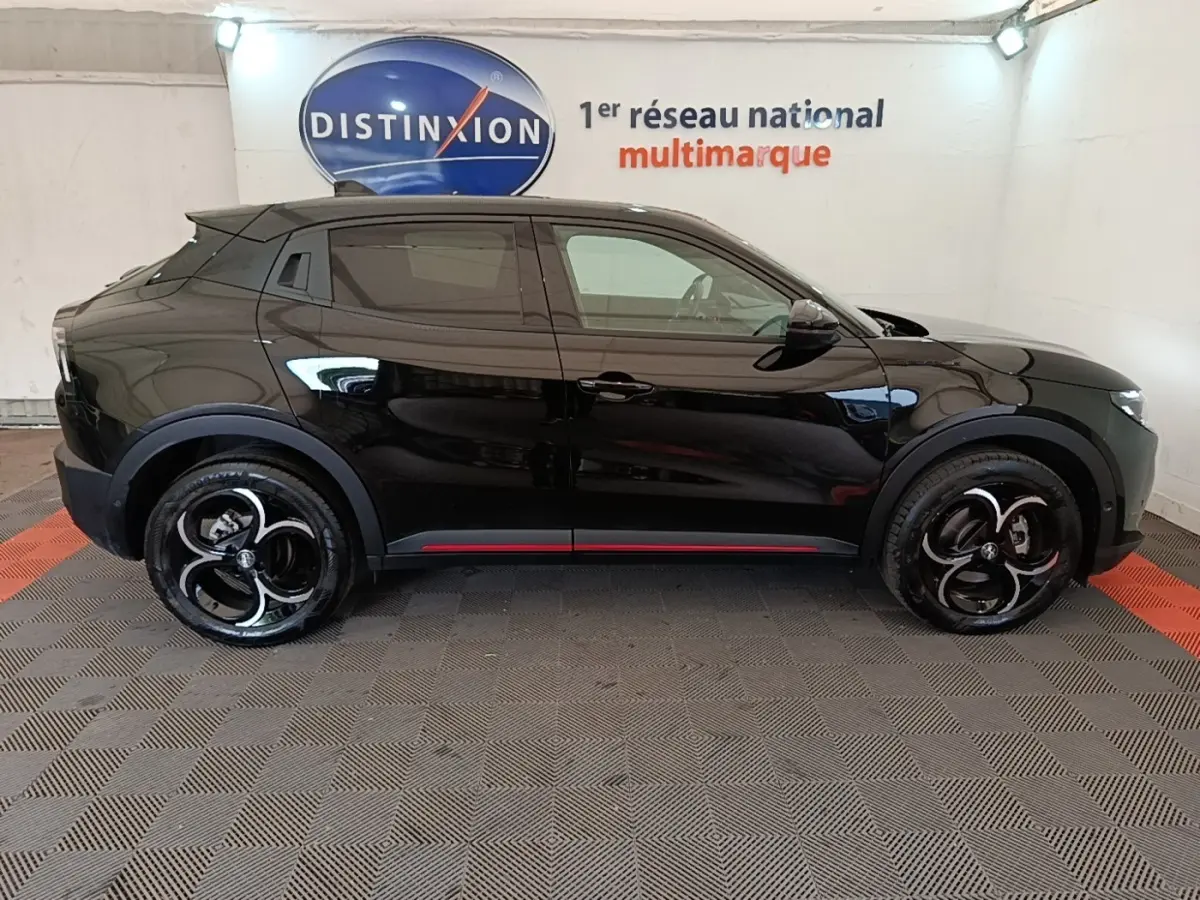 Vue de profil côté gauche d'une Alfa Romeo Junior noire avec jantes noires et détails rouges sur le bas de caisse.