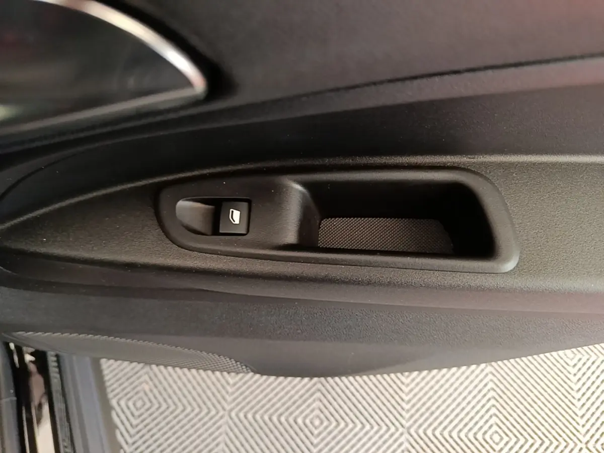 Gros plan sur la commande de lève-vitre côté intérieur d'une Alfa Romeo Junior noire, avec poignée de porte intégrée.