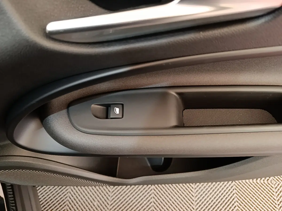 Détail de la poignée intérieure côté gauche de la porte d’une Alfa Romeo Junior 1.2 Ibrida noire, avec bouton de verrouillage.