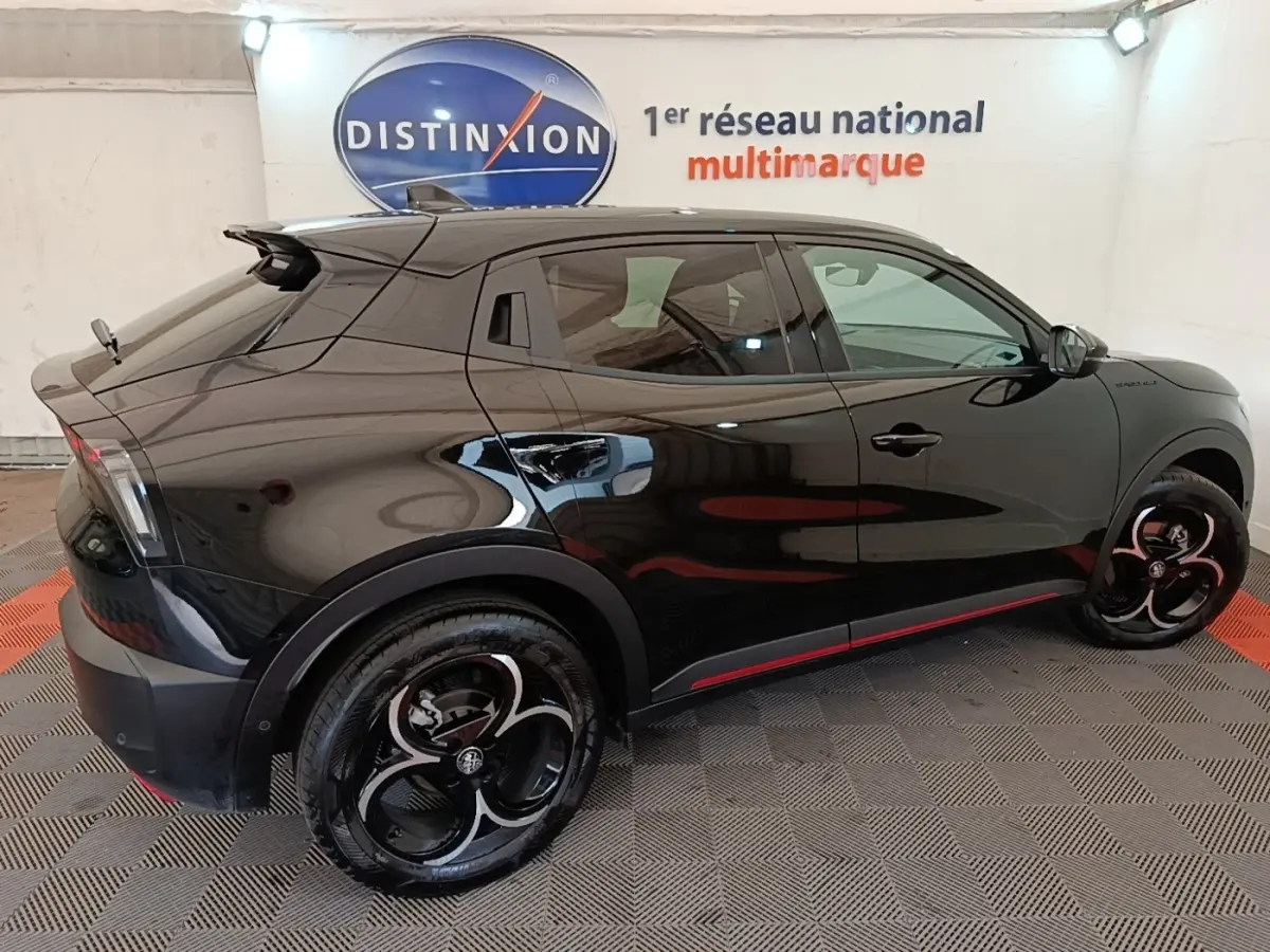 Vue latérale droite d'une Alfa Romeo Junior noire 2024 avec jantes noires et détails rouges sur bas de caisse.