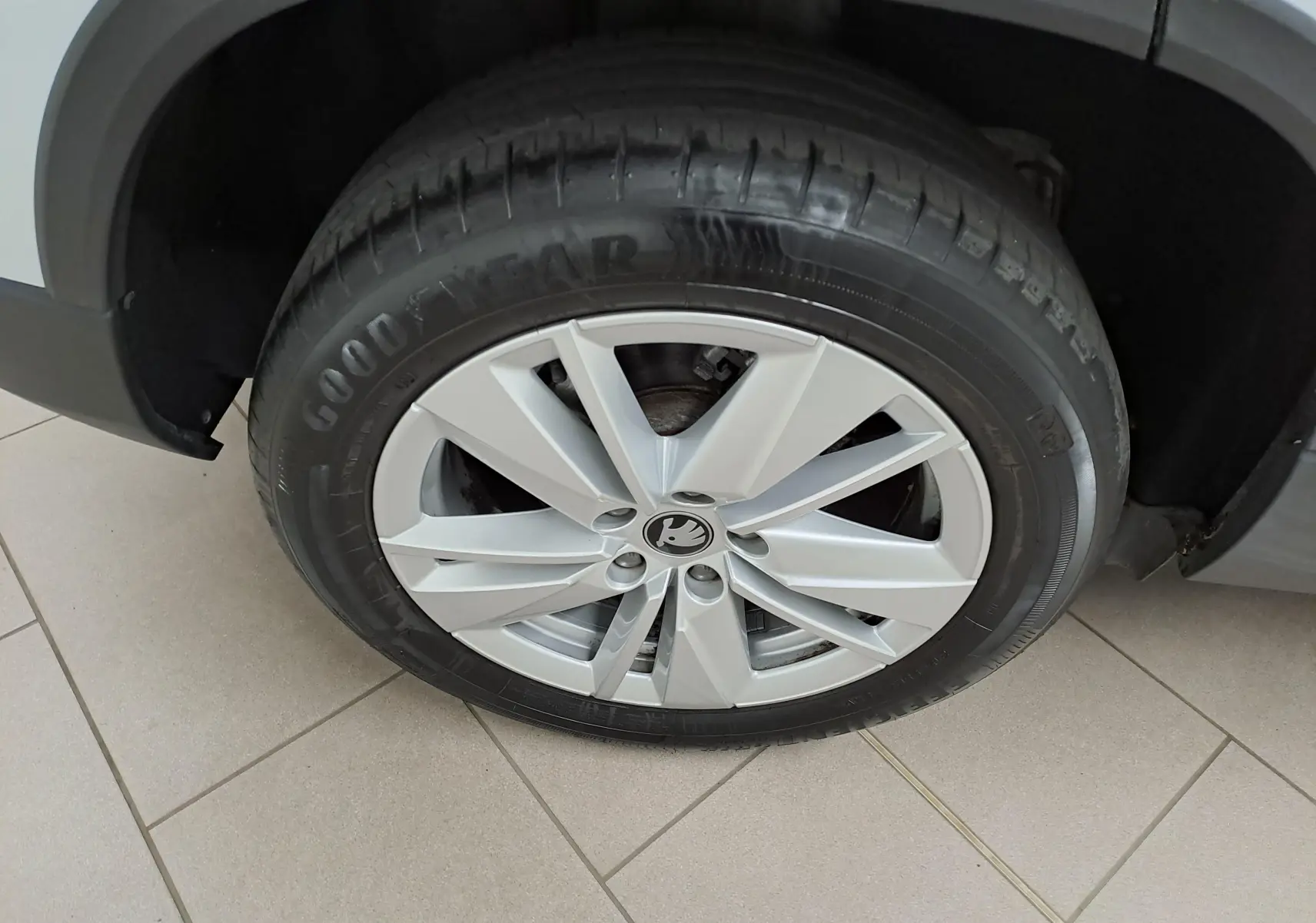 Gros plan sur la roue avant gauche du Skoda Karoq blanc lune 2025, mettant en valeur la jante alliage et le pneu Goodyear.