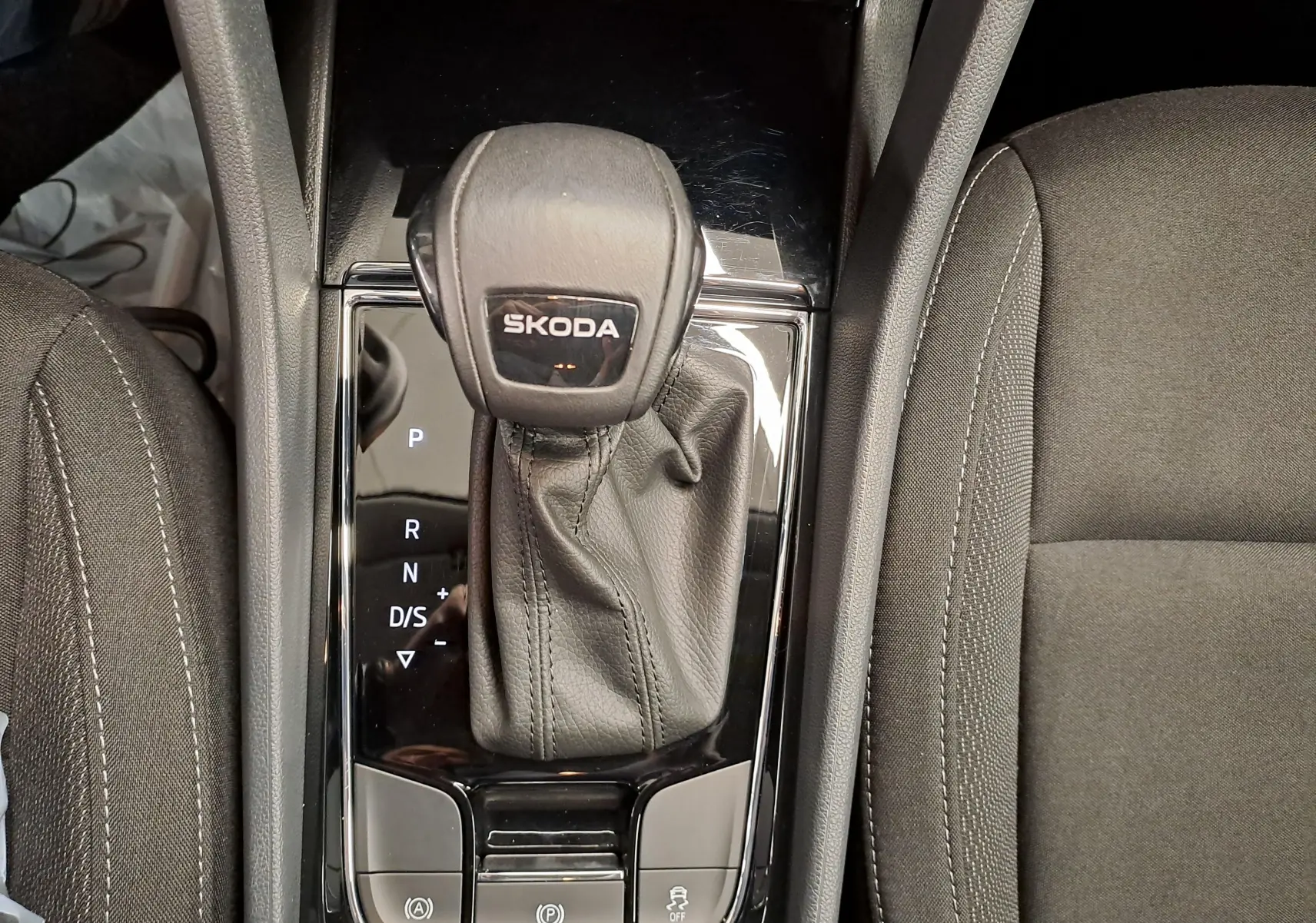 Vue rapprochée de la console centrale du Skoda Karoq 2025, levier de vitesse automatique en cuir noir avec logo Skoda.