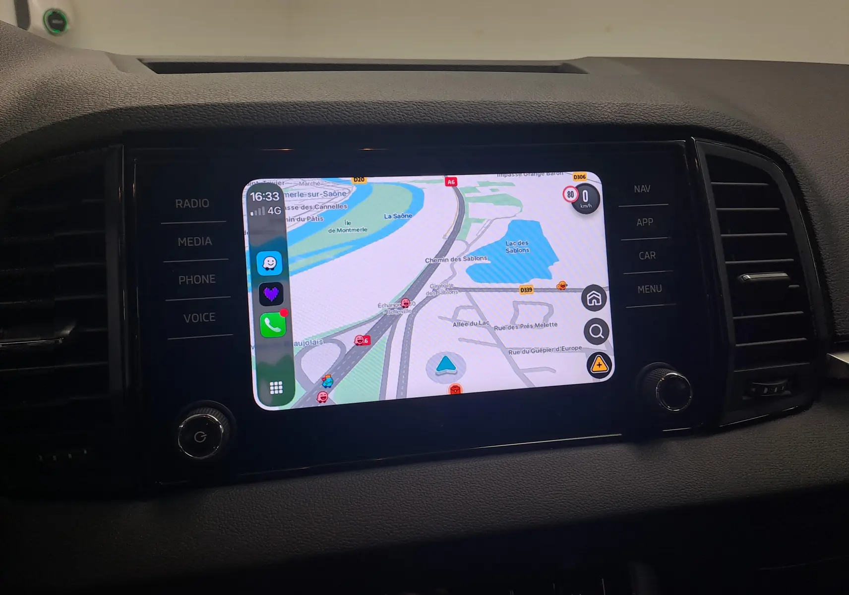 Écran central tactile du Skoda Karoq 2025 blanc lune, affichant une carte de navigation avec commandes latérales.