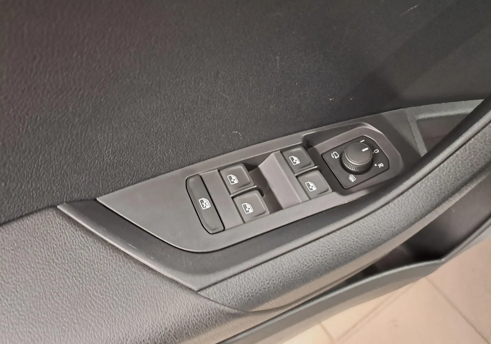 Commande des vitres et réglage des rétroviseurs sur la porte côté gauche d’un Skoda Karoq 2025 noir.