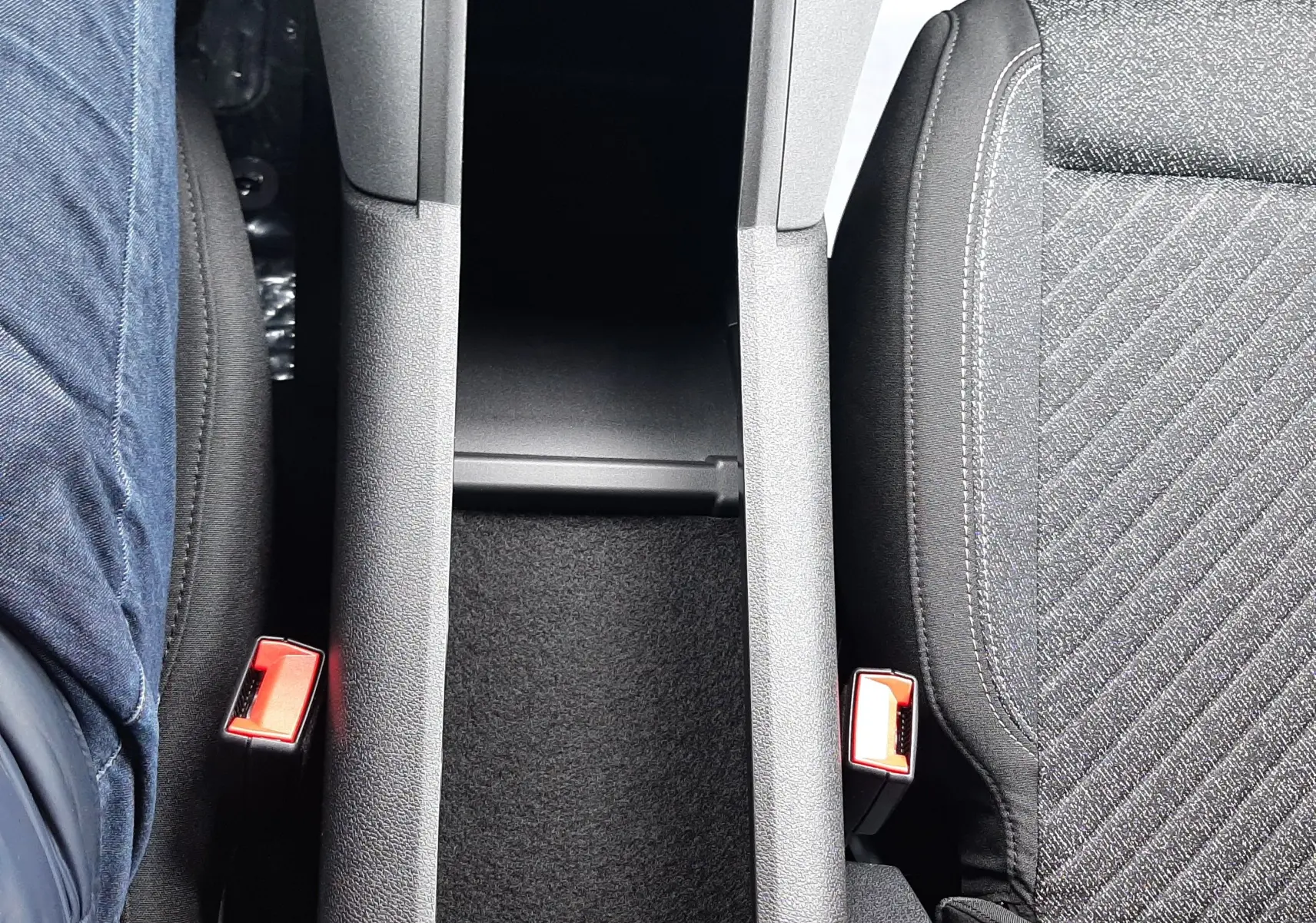 Vue plongeante sur la console centrale noire et les sièges tissu gris du Peugeot Rifter Bleu Kiama, version 2026.