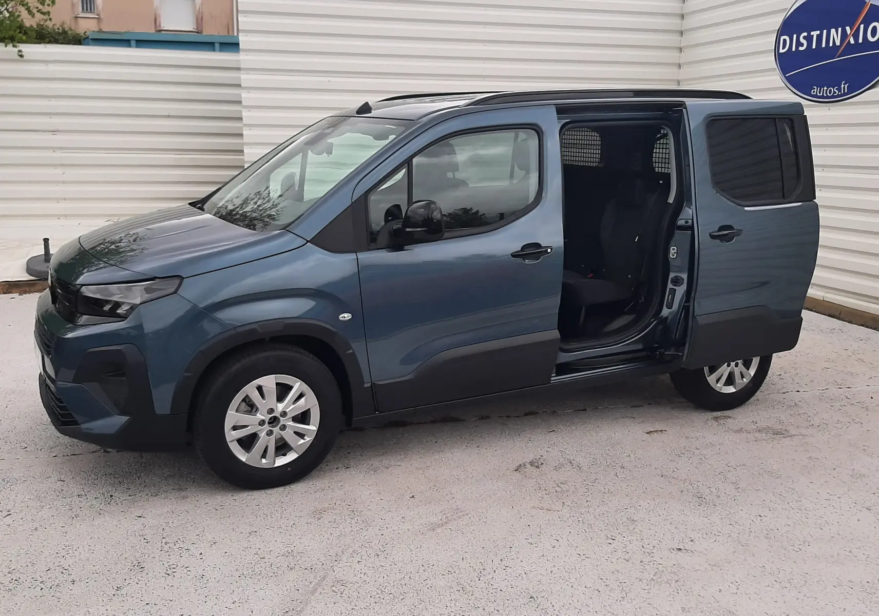 Vue de profil droit d'un Peugeot Rifter bleu Kiama 2026 avec porte latérale coulissante ouverte et jantes alu 16 pouces.