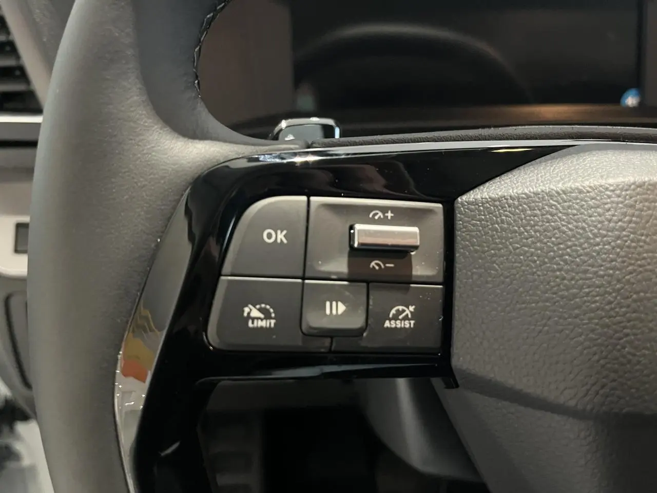 Gros plan sur les commandes à gauche du volant en cuir noir du Peugeot Expert Fourgon blanc 2024.