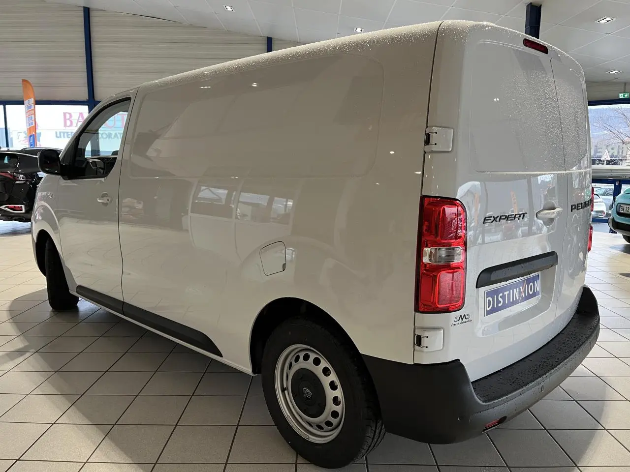 Vue 3/4 arrière droit du Peugeot Expert Fourgon blanc 2024 en intérieur, avec feux arrière et porte latérale visibles.