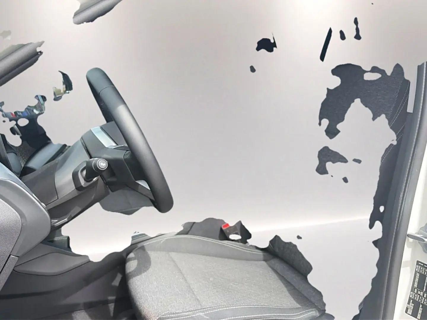 Intérieur côté conducteur de BMW Série 1 blanc pur 2025, siège sport gris et volant cuir M visible.