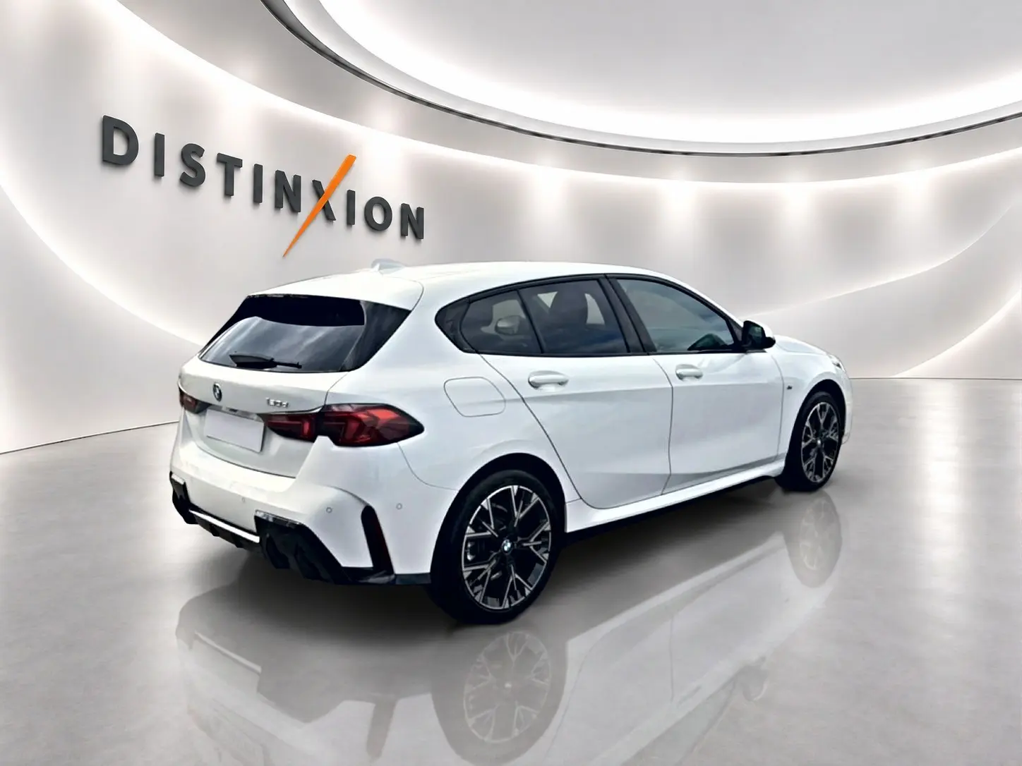 BMW Série 1 blanche vue en 3/4 arrière droit, avec jantes sport noires et détails M Sport visibles.