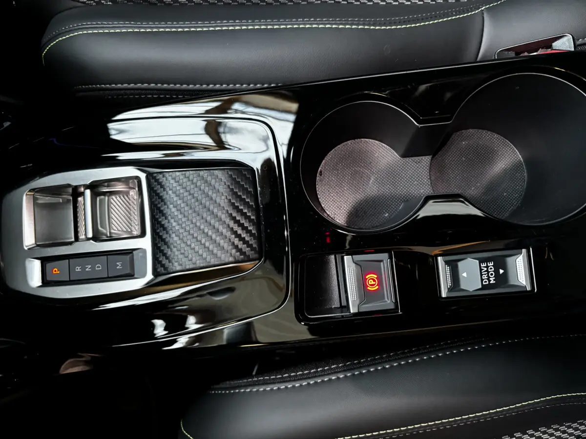Gros plan sur la console centrale noire brillante de la Peugeot 208 Hybrid 136 eDCS6 GT avec levier de vitesses et boutons électroniques.