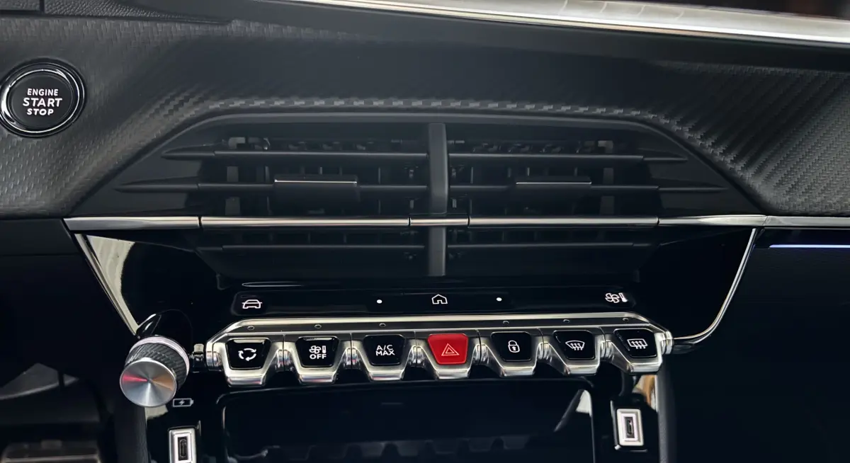 Détail du tableau de bord de la Peugeot 208 Hybrid 136 eDCS6 GT 2024 avec commandes chromées et bouton start/stop noir.