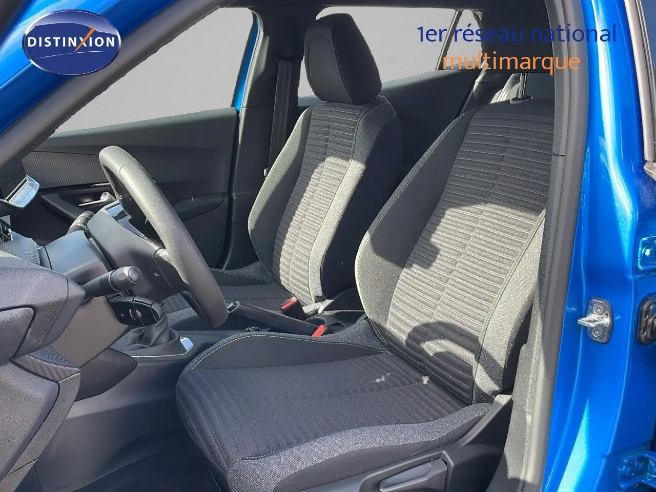 Intérieur de la Peugeot 2008 2024 en bleu Vertigo, vue côté gauche sur les sièges avant en tissu noir et gris.