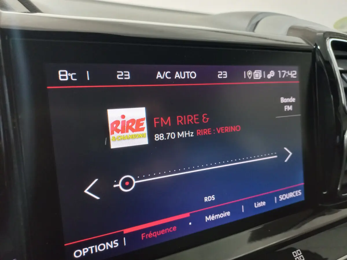 Gros plan sur l'écran tactile central du Citroën C5 Aircross blanc, affichant la radio FM Rire & Chansons.