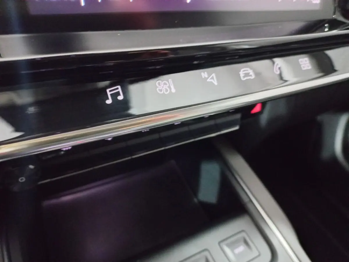 Gros plan sur la console centrale noire du Citroën C5 Aircross avec commandes tactiles éclairées en blanc.