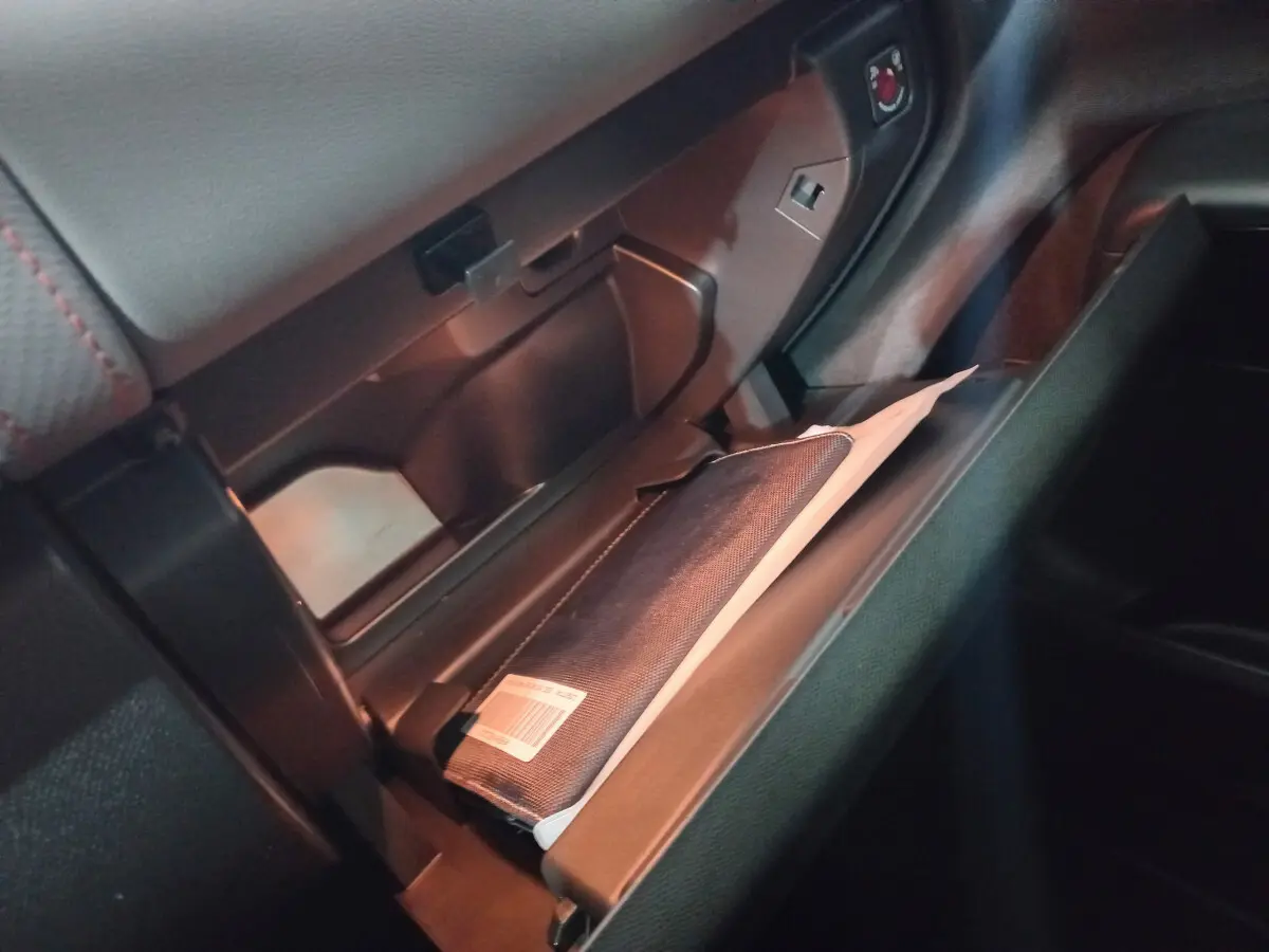 Gros plan sur la boîte à gants ouverte du Citroën C5 Aircross blanc, montrant un manuel dans un étui noir.