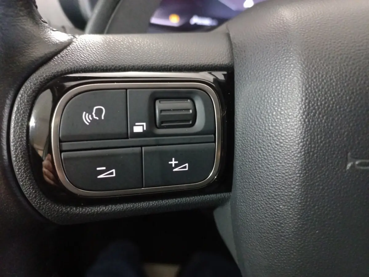Gros plan sur les commandes vocales et volume sur le côté gauche du volant cuir du Citroën C5 Aircross blanc.