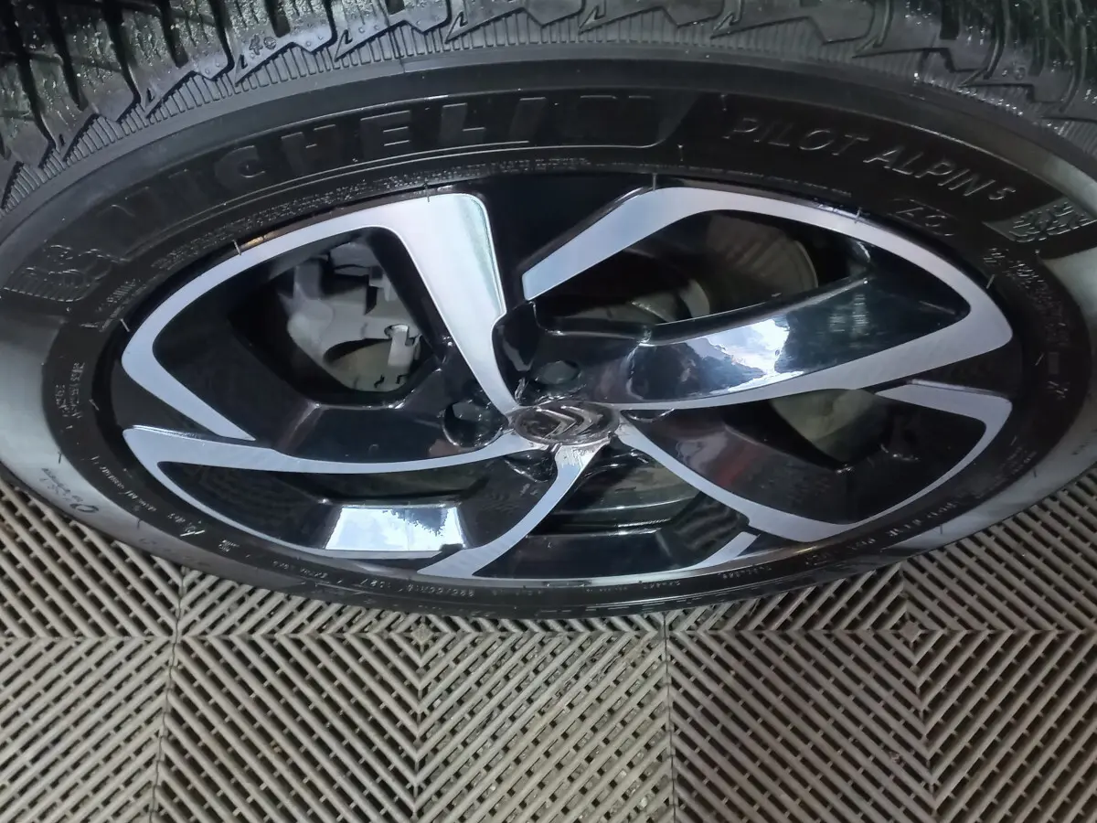 Gros plan sur la jante noire et argentée avec logo Citroën au centre, montée sur un pneu Michelin Pilot Alpin.