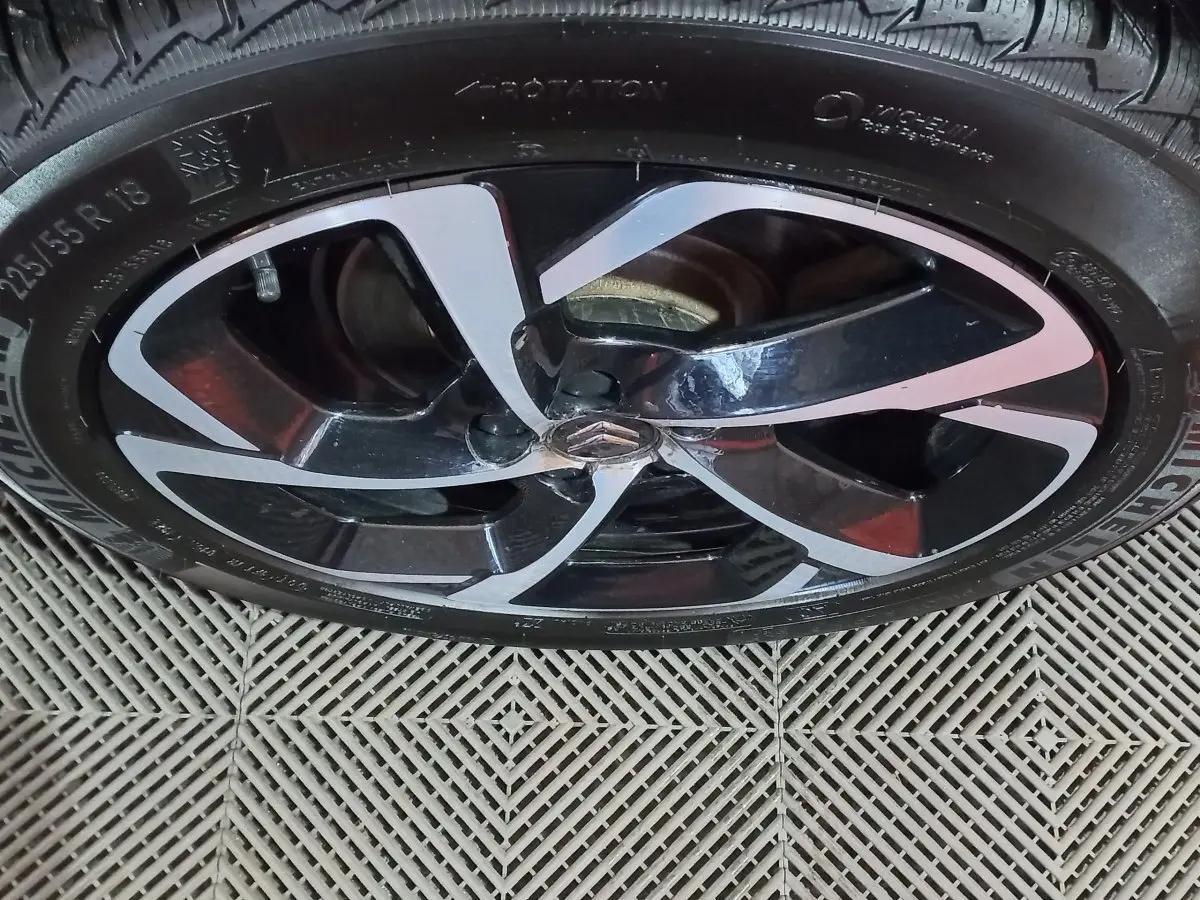 Gros plan sur la jante noire et argentée avec logo Citroën au centre d’un pneu Michelin monté sur un C5 Aircross blanc.