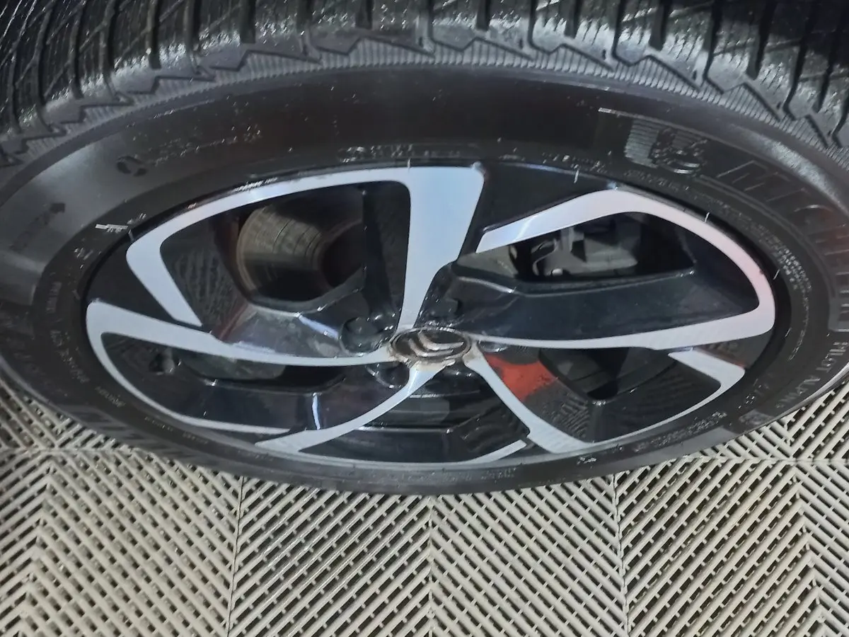 Gros plan sur la jante noire et argentée du Citroën C5 Aircross blanc, montrant le logo central et le pneu Michelin.