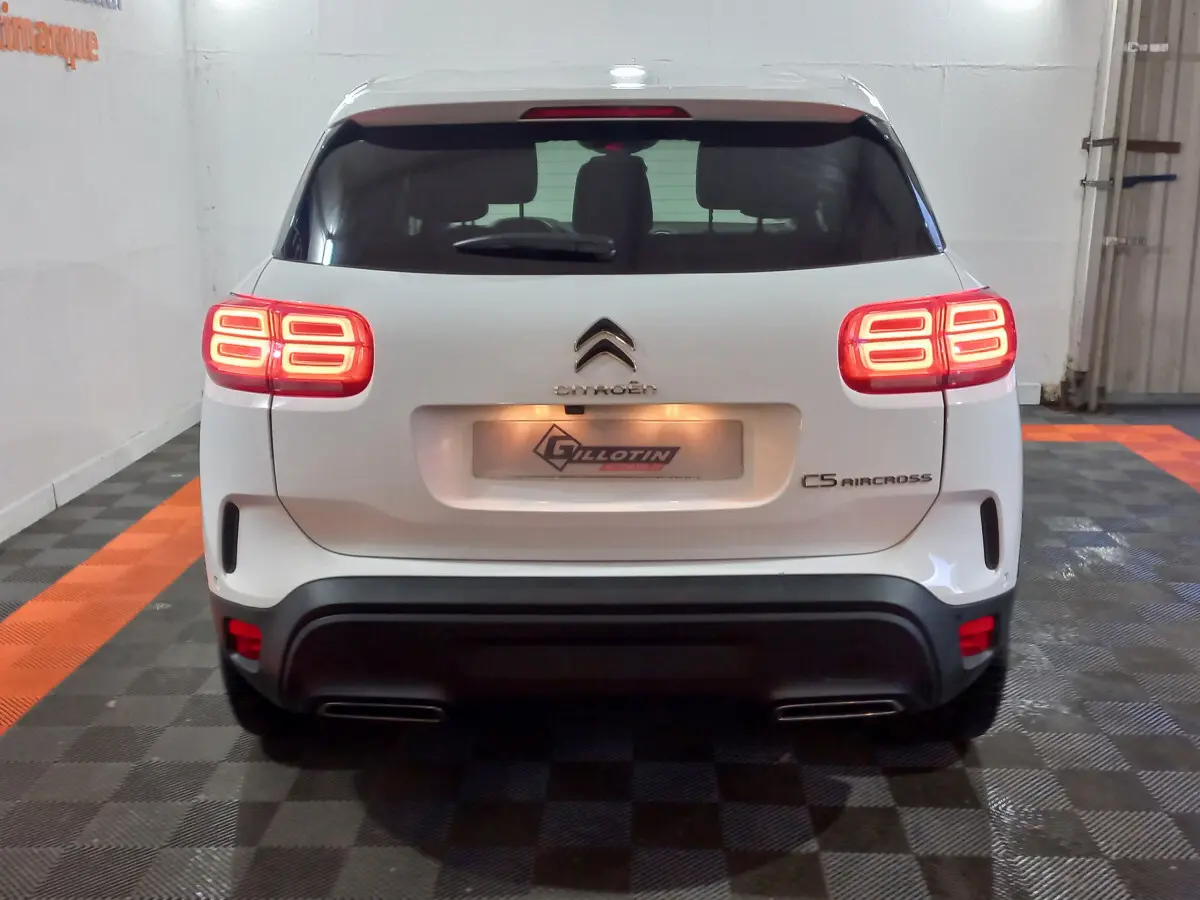 Vue arrière d'un Citroën C5 Aircross blanc avec feux arrière allumés dans un garage intérieur.