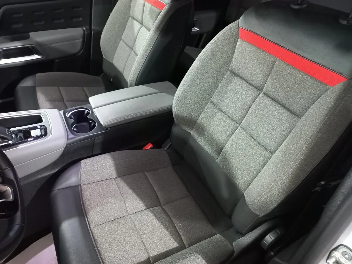 Vue rapprochée des sièges avant gris avec surpiqûres rouges et console centrale du Citroën C5 Aircross blanc.